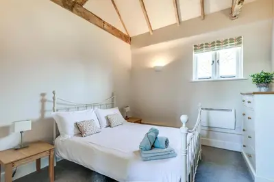 a bedroom with a white bed and a window at Harestreet Farm Barns, The Dairy, Parlour and Creamery in Cottered