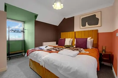 a bedroom with a large bed with orange and green walls at Harland Haven Spacious 4br House In Ipswich in Ipswich