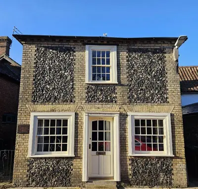 a brick house with white windows and a door at The Old Flint Bank Cottage in Harleston