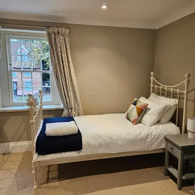 a bedroom with a white bed and a window at The Old Flint Bank Cottage in Harleston