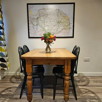 a table with a vase of flowers and a map at The Old Flint Bank Cottage in Harleston