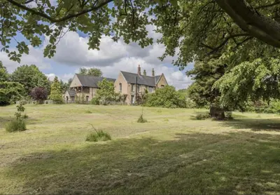 a large house in the middle of a field at Cockayne Hatley Hall in Cockayne Hatley