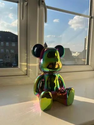 a small colorful teddy bear sitting in front of a window at The Nook - Town Centre Apartment in Hoddesdon