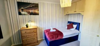 a bedroom with a bed and a dresser and a painting at Chelmsford Comfort Retreat Spacious 4 Bedroom Sleeps 7 Free Parking in Widford