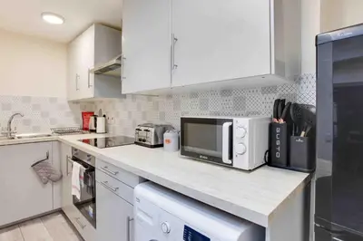 a kitchen with white cabinets and a counter with a microwave at Elm Cottage Ipswich in Ipswich