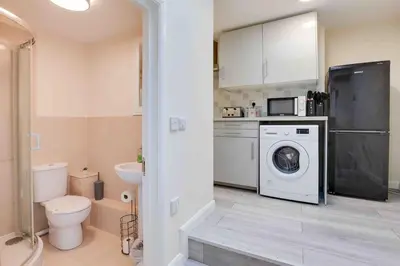 a bathroom with a washing machine and a washer at Elm Cottage Ipswich in Ipswich