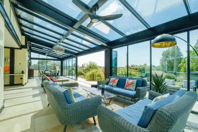 a conservatory with blue furniture and glass windows at Mill House in Thorpeness