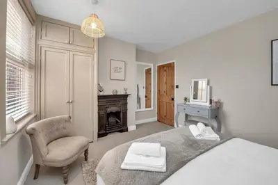 a bedroom with a bed and a chair and a fireplace at Delightful 10 St Martins - 2 bed, 2 bathroom with parking available in Bury Saint Edmunds