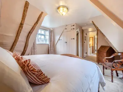 a bedroom with a large white bed in a attic at All Saints Cottage in Saffron Walden