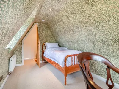 a small bedroom with a bed and a staircase at All Saints Cottage in Saffron Walden