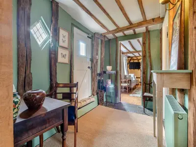 a living room with green walls and a table at All Saints Cottage in Saffron Walden
