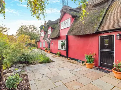 a red house with a gray roof at All Saints Cottage in Saffron Walden
