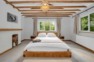 a bedroom with a large bed and a fireplace at Stunning 2 Lodge Cottage retreat in Little Saxham