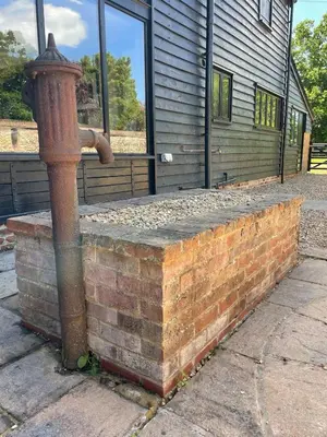 a fire hydrant on a brick wall in front of a building at Kings Barn - English Countryside Retreat in Lindsell