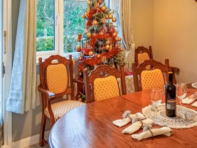 a dining room table with a christmas tree in the background at Ivy Rose Cottage in Ipswich