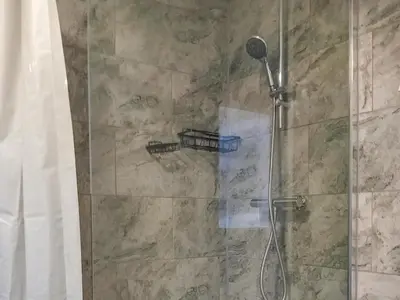 a shower with a glass door with a shower head at Ivy Rose Cottage in Ipswich