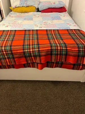 a bed with an orange and red blanket on it at Double room in Canvey island with shared bathroom in Hadleigh
