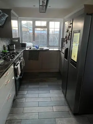 a kitchen with a refrigerator and a tile floor at Double room in Canvey island with shared bathroom in Hadleigh