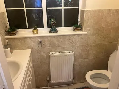 a bathroom with a sink and a toilet and a window at Double room in Canvey island with shared bathroom in Hadleigh