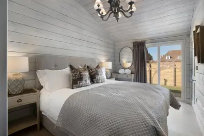 a bedroom with a bed and a chandelier and a window at Orchard Cottage in Saint Osyth