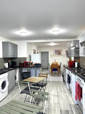 a kitchen with a table and chairs in it at Penn Gardens Spacious king size room- 3 in Friern Barnet