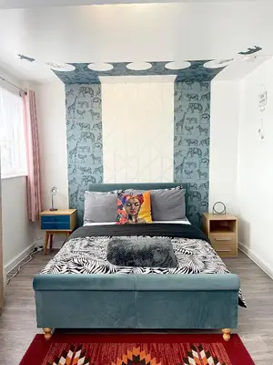 a bedroom with a large bed with blue walls at Penn Gardens 2 beds Apartment-2 in Friern Barnet