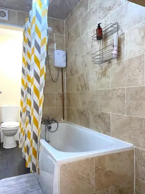 a bathroom with a tub and a toilet at Penn Gardens 2 beds Apartment-2 in Friern Barnet