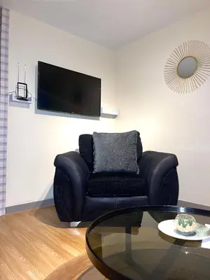 a living room with a black couch and a glass table at Penn Gardens Spacious 2 Beds - 1 in Friern Barnet