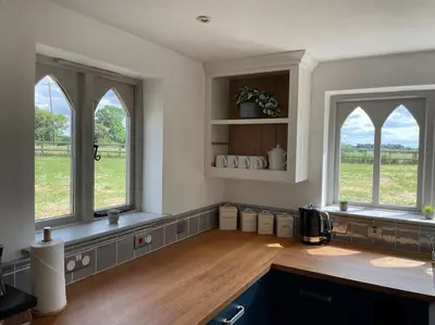 a kitchen with three windows and a wooden counter top at Old Cottage - English Countryside Retreat in Lindsell