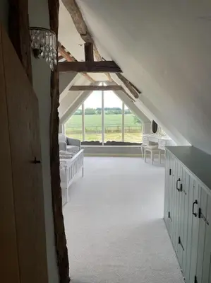 an attic room with a large window and white furniture at Old Cottage - English Countryside Retreat in Lindsell