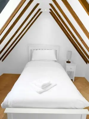a white bed in a room with wooden beams at Mallards - English Countryside Retreat in Lindsell