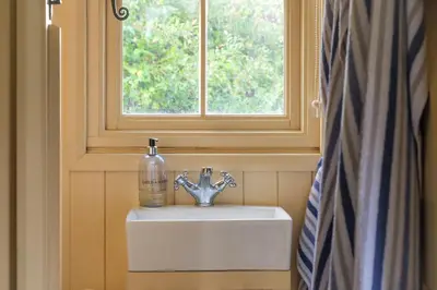 a sink with a soap bottle on it in a bathroom at Hill Top Hideaway Shepherds Hut with Hot Tub in Woodham Mortimer
