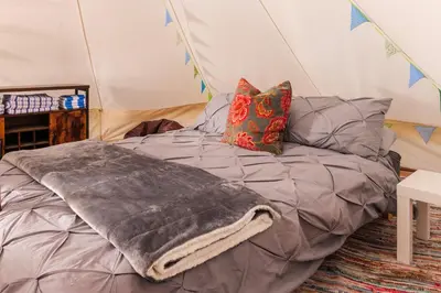 a bed in a tent with a blanket on it at Hill Top Hideaway Shepherds Hut with Hot Tub in Woodham Mortimer
