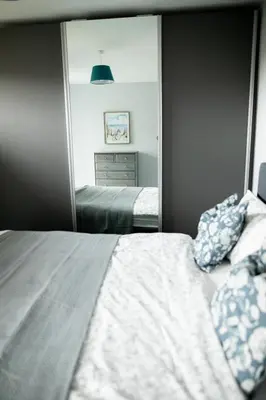 a bedroom with a bed in front of a mirror at Lovely 3 Bedroom House in Chelmsford in Chelmsford