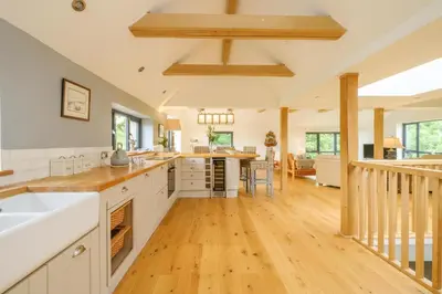 an open kitchen with white cabinets and wooden floors at Sandown in Snape