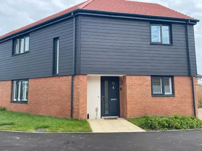 a black house with a red brick at Cosy room in Great Bromley