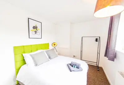 a bedroom with a white bed with a green headboard at Contractor's Haven 4BED 2BATH House in Ipswich with FREE Parking in Ipswich