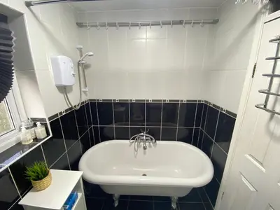 a white sink in a bathroom with black tiles at Single Room Near Basildon City Centre in Basildon