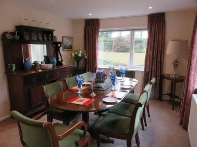 a dining room with a wooden table and green chairs at Tresco - Aldeburgh's hidden gem in Aldeburgh