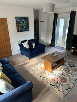 a living room with a blue couch and a coffee table at The Snug at Fourleys in Woodhurst