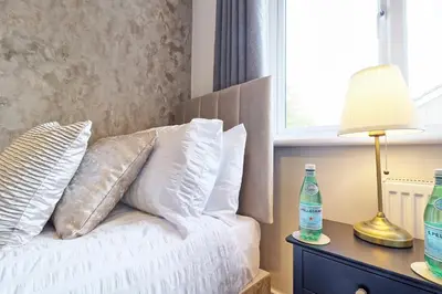 a bed with white pillows and a lamp on a table at Modern 5-Bed Property, Ideal for Extended Business & Contractor Stays in Colchester