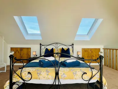a bedroom with a bed with blue pillows and windows at Unique Apartment with Stunning Views 2B in Felixstowe