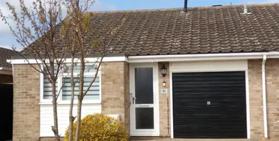 a house with a black garage door at Rainbow on Sea Frinton-on-Sea in Kirby Cross