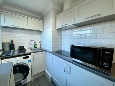 a kitchen with white cabinets and a microwave at The Annex in Tostock