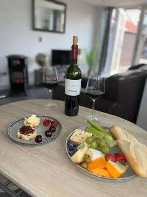 a table with two plates of food and a bottle of wine at Little Brook Retreat in Chelmsford