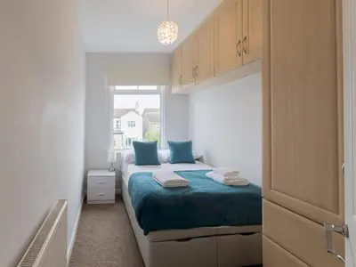 a bedroom with a bed with blue pillows and a window at Cosy Flat in Leigh Sea View - Pass the Keys in Southend-on-Sea