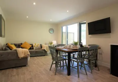 a living room with a dining room table and chairs at Copper Beech Lodge with Hot Tub, Games Room, Fire Pit in Toppesfield