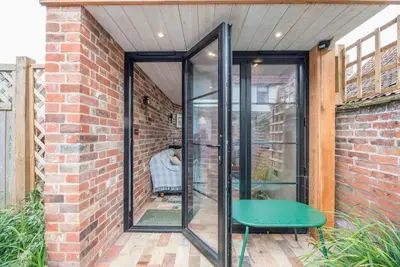an extension to a brick building with a green bench at Blythburgh Cottage, Yoxford in Yoxford