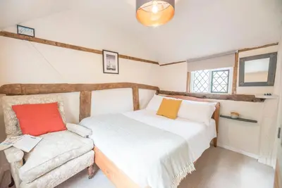 a bedroom with two beds and a chair at Blythburgh Cottage, Yoxford in Yoxford