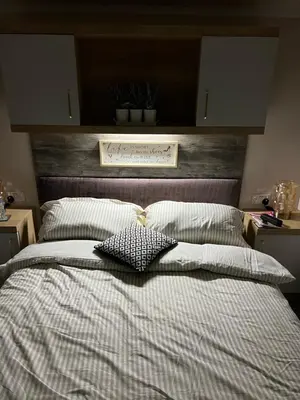 a bedroom with a large bed with a wooden headboard at Mimosa lodge in Little Clacton